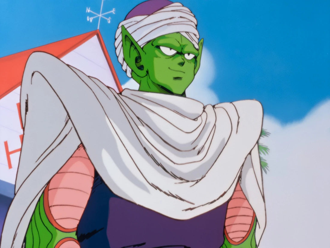 Piccolo, with green skin, a white turban and a long white cape, smirks under a blue sky, in front of a red roof topped with a weather vane.