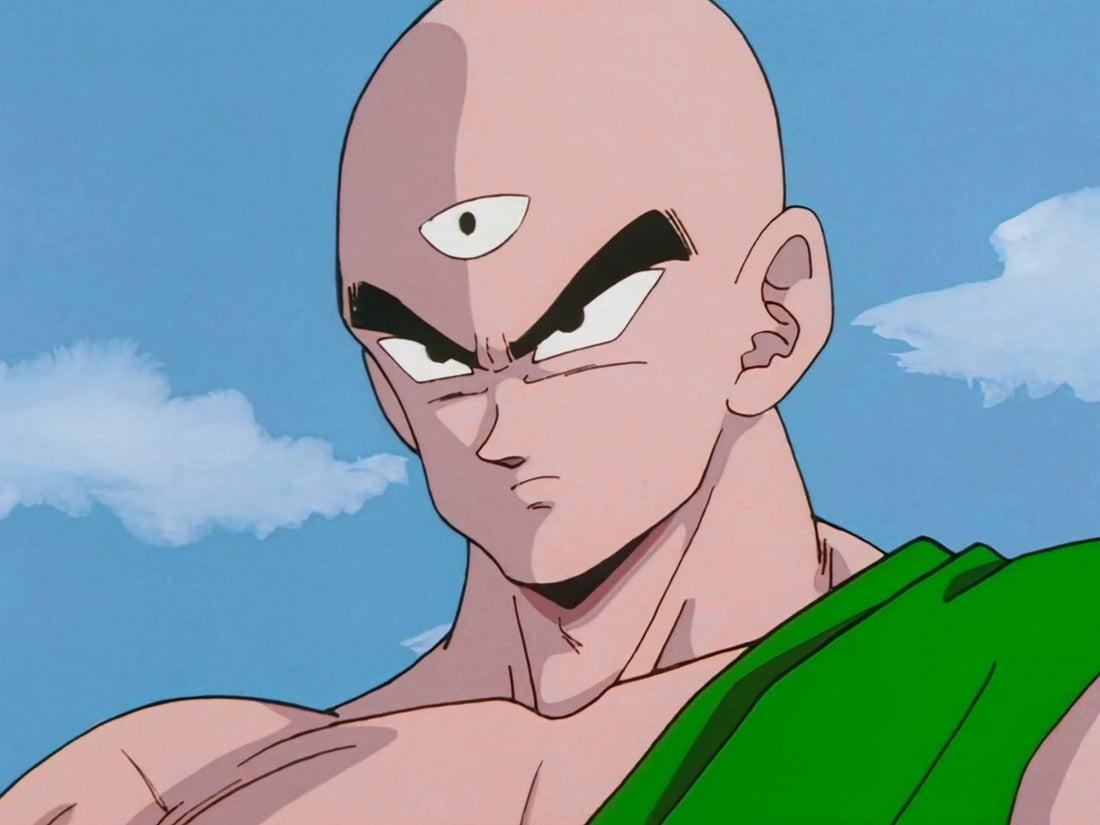 Close-up of Tien Shinhan, shaved head and third eye in the middle of his forehead, brow furrowed, a green cloth over his shoulder, against a cloudy blue sky.