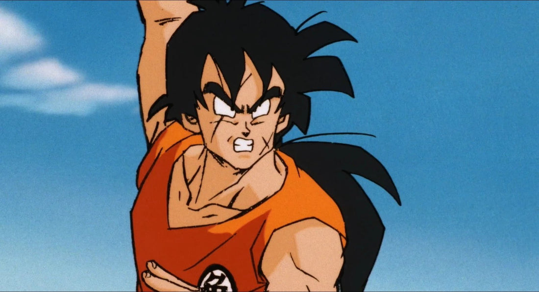 Yamcha aux cheveux longs, cicatrices au visage, lève le bras en serrant les dents, vêtu d'un gi orange, sur fond de ciel bleu.